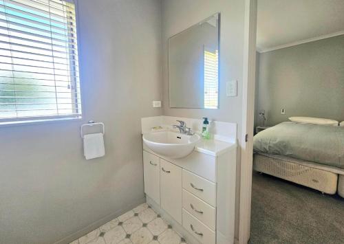ein weißes Bad mit einem Waschbecken und einem Bett in der Unterkunft Cozy Private Villa in Oropi in Oropi