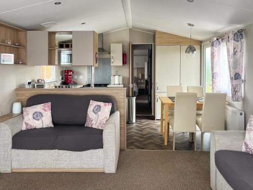 a living room and kitchen with a couch and a table at Woodend Caravan in Lairg