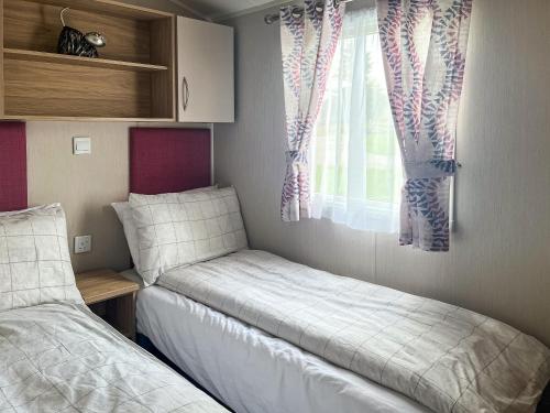 a bedroom with two beds and a window at Woodend Caravan in Lairg