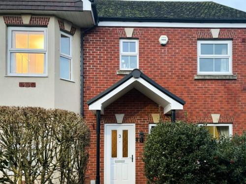 une maison en briques rouges avec une porte blanche dans l'établissement Melrose Walk, à Tewkesbury