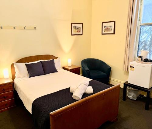 WallerawangにあるThe Commercial Hotel Wallerawangのベッドルーム1室(ベッド1台、椅子付)