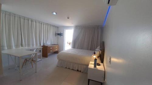 PH1401 Hotel Margarita Real في بورلامار: غرفة نوم بسرير وطاولة ومكتب