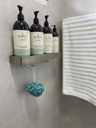 four bottles of wine on a shelf in a bathroom at Sunshine Retreat Modern 3BR Haven in St Marys