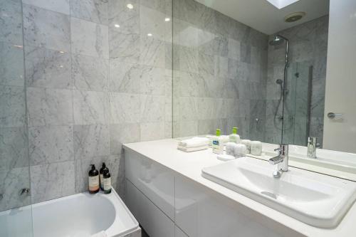 a white bathroom with a sink and a shower at Sophisticated art deco in the heart of Toorak in Melbourne