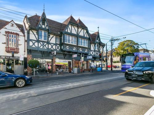 a city street with cars driving past a building at Sophisticated art deco in the heart of Toorak in Melbourne
