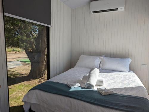 a bedroom with a bed with towels and a window at Tiny House 14 at Grampians Edge in Dadswells Bridge