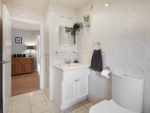 a white bathroom with a toilet and a sink at Fircroft in Glencarse
