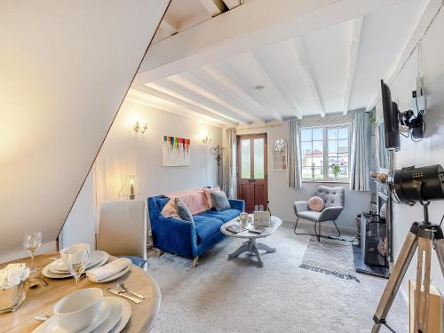 ein Wohnzimmer mit einem blauen Sofa und einem Tisch in der Unterkunft Crompton Cottage in Bretforton