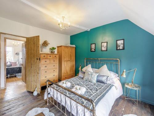 1 dormitorio con cama y pared azul en Crompton Cottage, en Bretforton