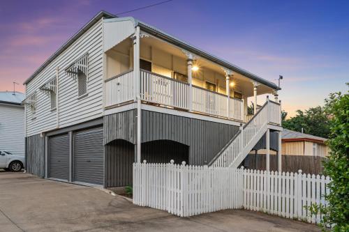 a house with a white fence in front of it at Spacious and Charming Queenslander in Ipswich in Bundamba