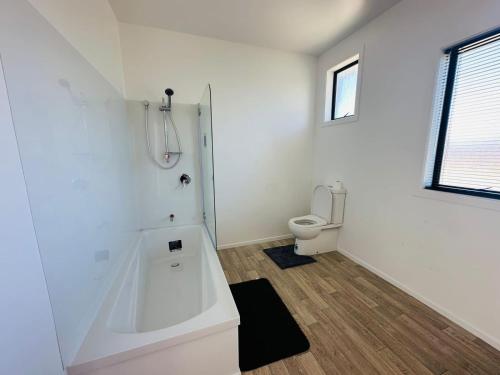 a white bathroom with a toilet and a window at Double bed room in Invercagill/5mini walk to city in Invercargill