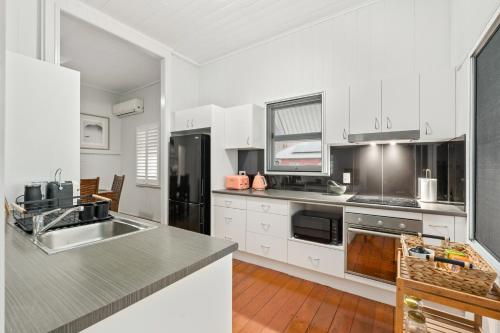 a kitchen with white cabinets and stainless steel appliances at Spacious and Charming Queenslander in Ipswich in Bundamba