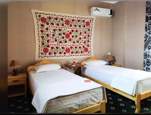 2 camas en una habitación con una manta en la pared en Guesthouse Anora en Samarcanda