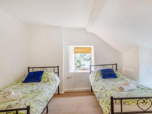 two beds in a room with a window at Jasmine Cottage in Osmington