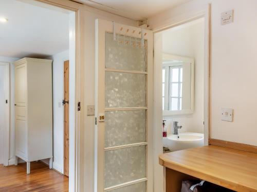 La salle de bains est pourvue d'une porte de douche en verre et d'un lavabo. dans l'établissement Jasmine Cottage, à Osmington