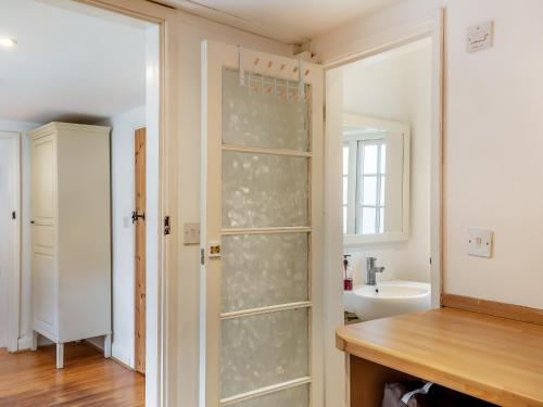 a bathroom with a glass shower door and a sink at Jasmine Cottage in Osmington