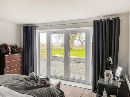 North End Cottage في Longframlington: غرفة نوم بسرير وباب زجاجي منزلق