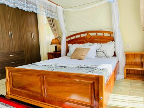 a bedroom with a wooden bed with a canopy at 3 bedroom apartment in Mirembe Villas Kigo, Kampala, Entebbe Uganda in Kigo