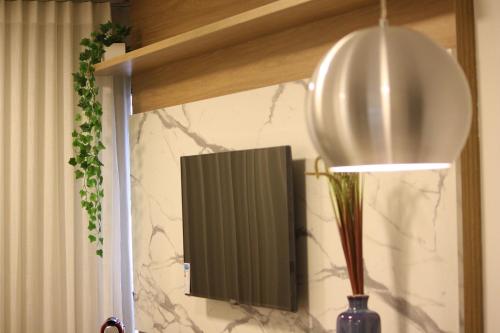 a light hanging from a wall with a vase and a lamp at Noroeste Easy by CentoEdez in Brasília