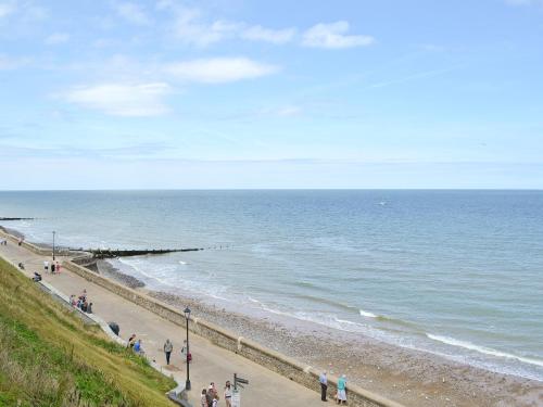 grupa ludzi spacerujących po plaży w obiekcie Stone Cottage w mieście Cromer