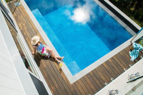 Un niño sentado en una terraza de madera junto a una piscina en The View, en Airlie Beach