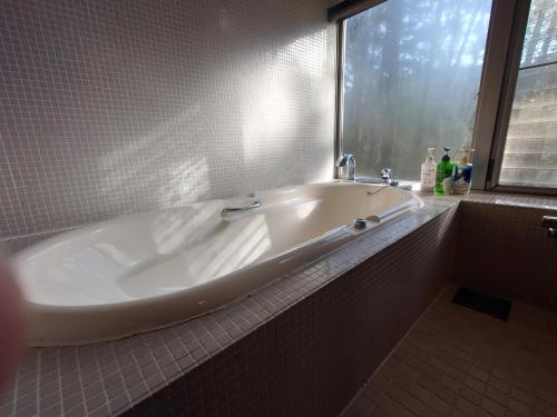 una vasca bianca in un bagno con finestra di Hotel Forest a Ōzu