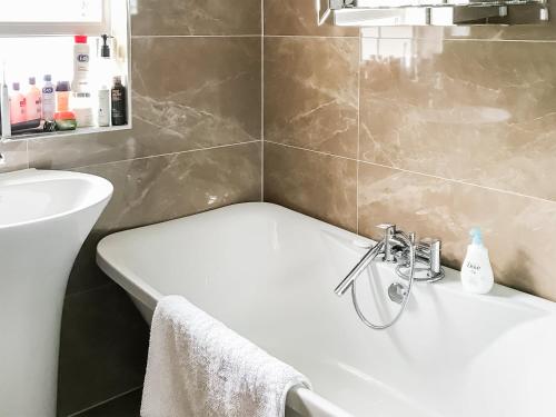 a bathroom with a white tub and a sink at Woodlea Farm in Four Marks