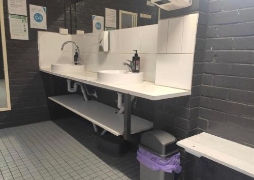a public bathroom with two sinks and a black wall at The Wannon 2 in Dadswells Bridge