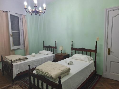 a bedroom with two beds and a chandelier at Casona Harguindeguy in Paysandú