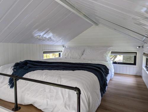 a bed in the middle of a white room at Tiny House 11 at Grampians Edge in Dadswells Bridge