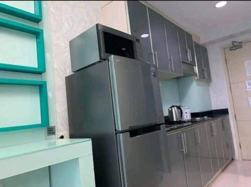 a kitchen with a stainless steel refrigerator and cabinets at Benedick Place at sea residences in Manila