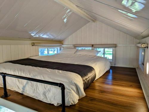 a bed in the middle of a room with wood floors at Tiny House 20 at Grampians Edge in Dadswells Bridge