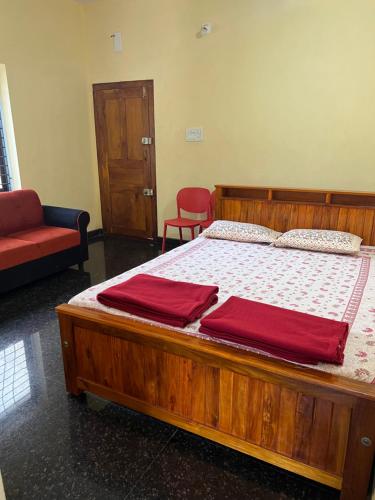 a bedroom with a wooden bed with two red sheets at Devatha Homestay, Guest House, Hotel,Dharmasthala-2 in Dharmastala