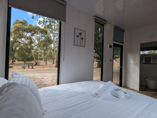 a bedroom with a white bed and a large window at Tiny House 12 at Grampians Edge in Dadswells Bridge