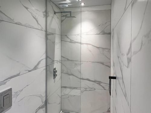 a bathroom with a shower with white marble walls at Peartree Cottage in Sheffield