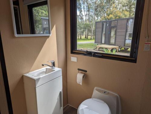 a bathroom with a toilet and a sink and a window at Tiny House 16B at Grampians Edge in Dadswells Bridge
