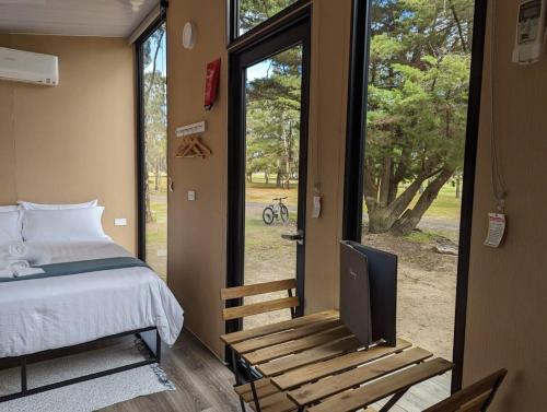 a bedroom with a bed and a tv and a window at Tiny House 16B at Grampians Edge in Dadswells Bridge