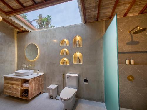 a bathroom with a toilet and a sink and a mirror at Uluwatu Desa in Uluwatu