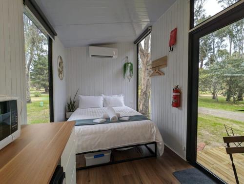 a bedroom with a bed and a large window at Tiny House 21 at Grampians Edge in Dadswells Bridge