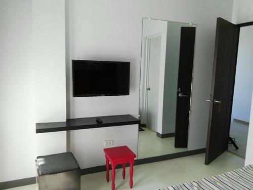 a living room with a red stool and a television at Le Vita Hotel in Santo Domingo