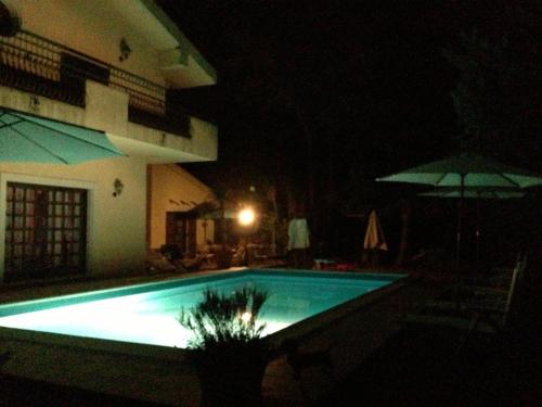 a swimming pool at night with an umbrella at B&B Rollo Garden in Ragusa
