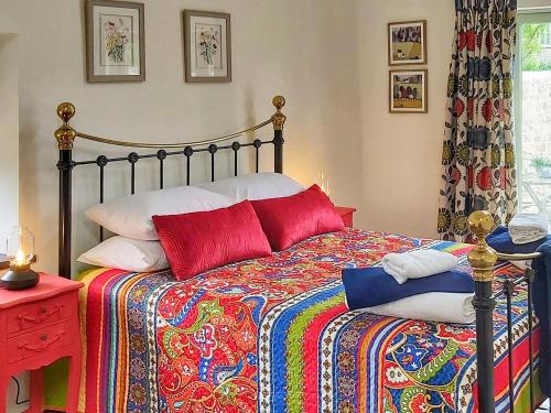 1 dormitorio con 1 cama con una manta y almohadas coloridas en Bramley - Uk37378, en Pilton