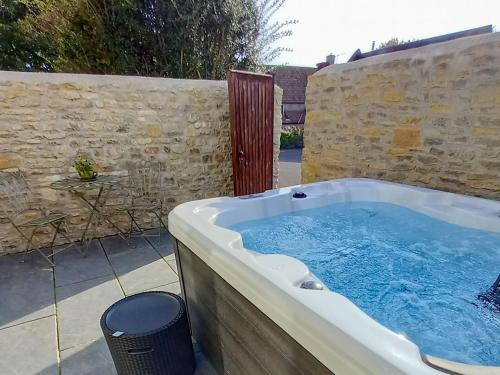a hot tub in a backyard with a stone wall at Bramley - Uk37378 in Pilton