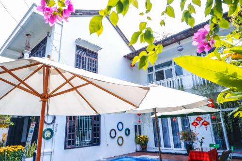 a white house with two umbrellas in front of it at Oleander Garden Homestay in Hoi An