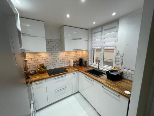 une cuisine avec des armoires blanches et des comptoirs en bois dans l'établissement Le coup de cœur d’Argelès, à Argelès-sur-Mer