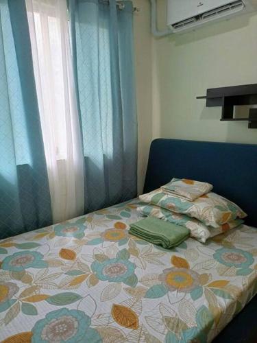a bedroom with a bed with a flowered blanket and a window at Grandiose Domicile in Basak