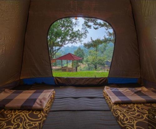 Una habitación con dos camas en una tienda de campaña con ventana. en Gunung Geulis Camp Area, en Pasirkuda