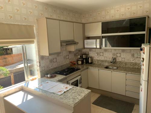 a kitchen with white cabinets and a stove top oven at Apto central completo com garagem in Caxias do Sul
