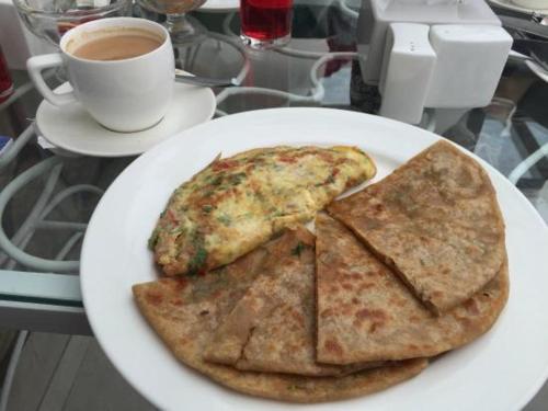 een bord met drie stukken pizza en een kop koffie bij Krishna Mahal Harmony in Vrindāvan