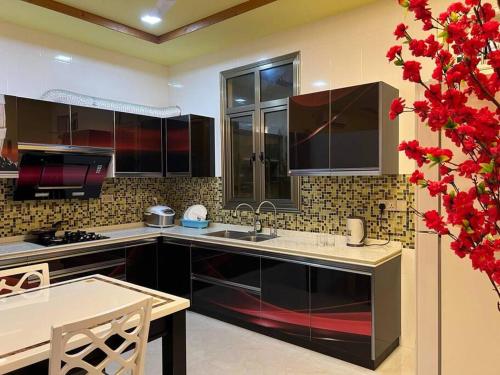 a kitchen with black cabinets and a table and red flowers at Saina Dive Residence - Fuvahmulah, Maldives in Fuvahmulah
